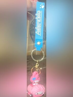 My Melody keychain with a molded mascot in pink vehicle with blue wristlet loop